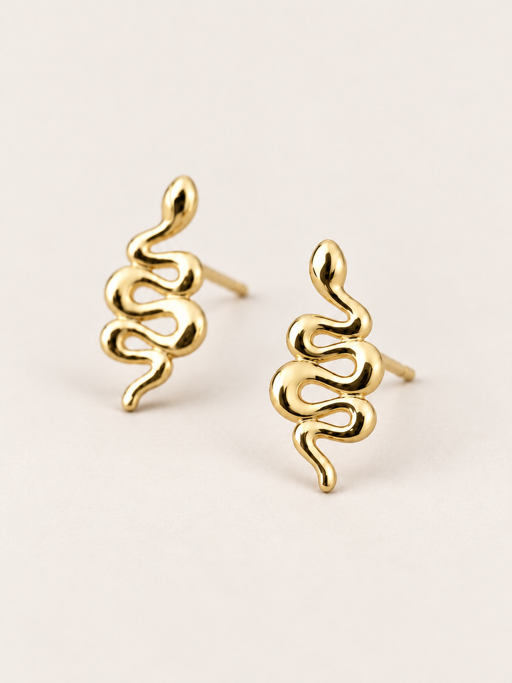 Gold Snake Stud Earrings shown angled on a warm neutral background