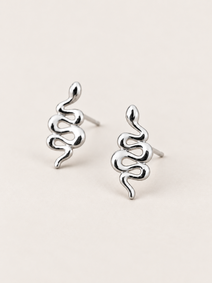Silver Snake Stud Earrings shown angled on a warm neutral background
