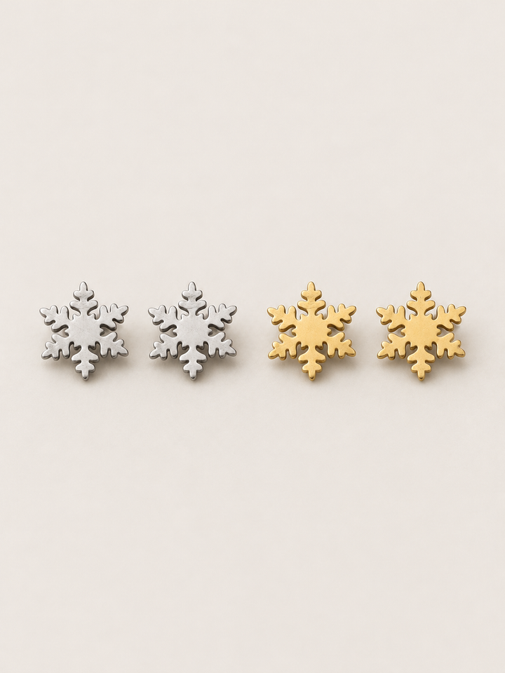 Silver and gold Snowflake Stud Earrings shown on a warm neutral background