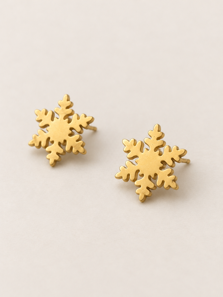 Gold Snowflake Stud Earrings shown angled on a warm neutral background