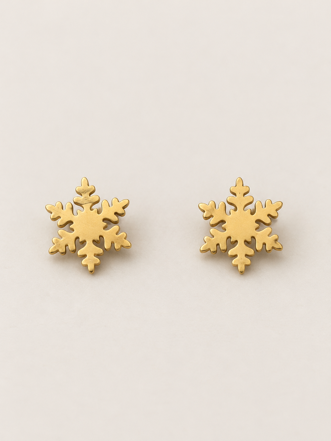 Gold Snowflake Stud Earrings shown on a warm neutral background