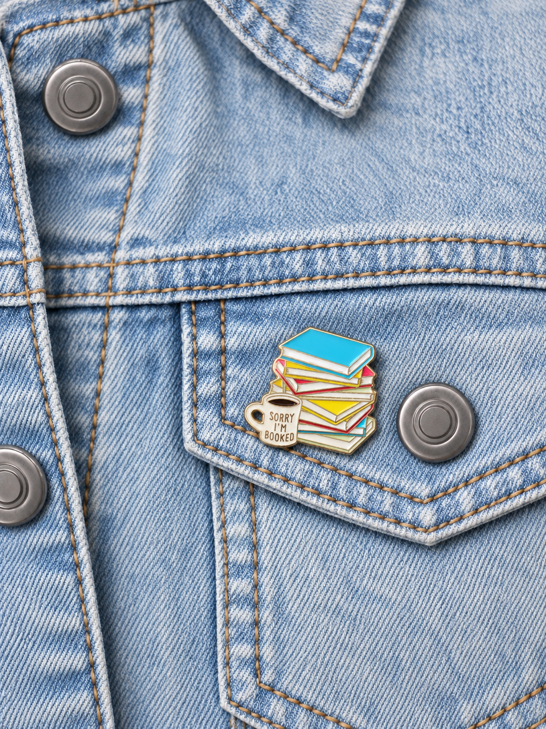 Sorry I’m Booked Pin displayed on light-wash denim beside a metal button
