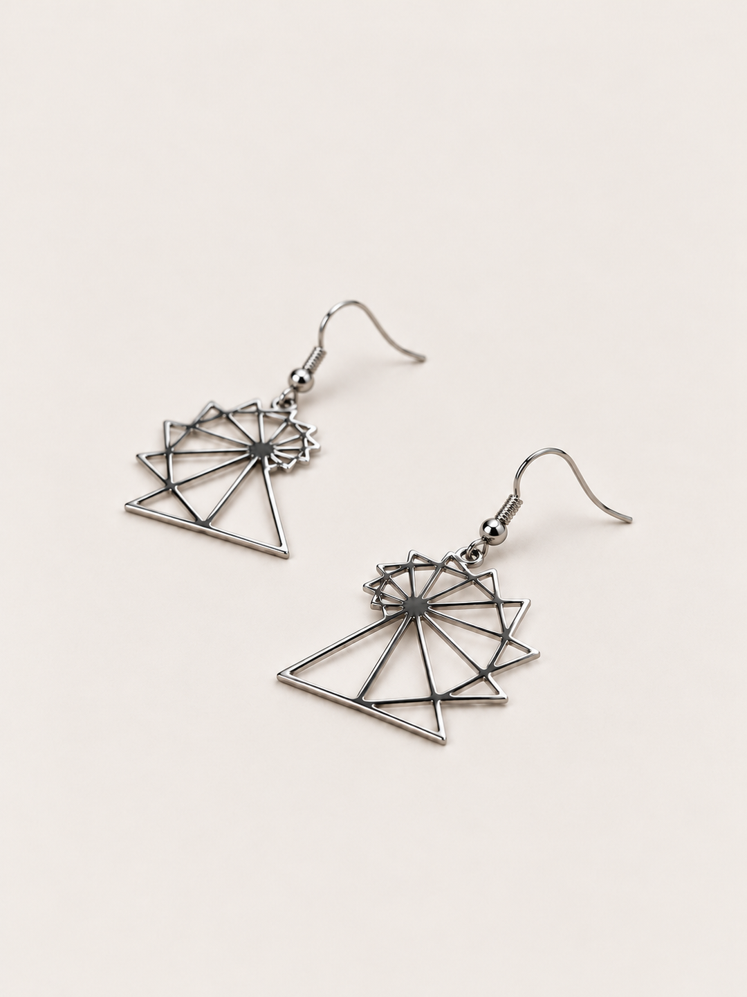Spiral of Theodorus Earrings in Silver lying flat at an angle on a warm neutral background
