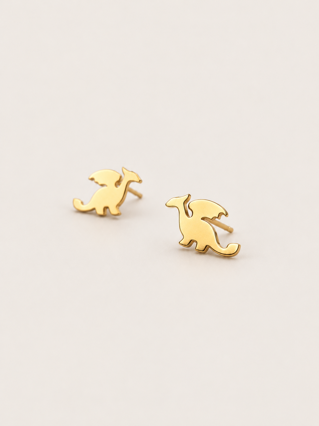 Gold angled Stainless Steel Dragon Stud Earrings on a warm neutral background