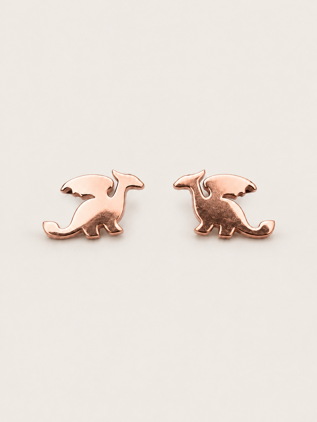 Rose Gold main Stainless Steel Dragon Stud Earrings on a warm neutral background