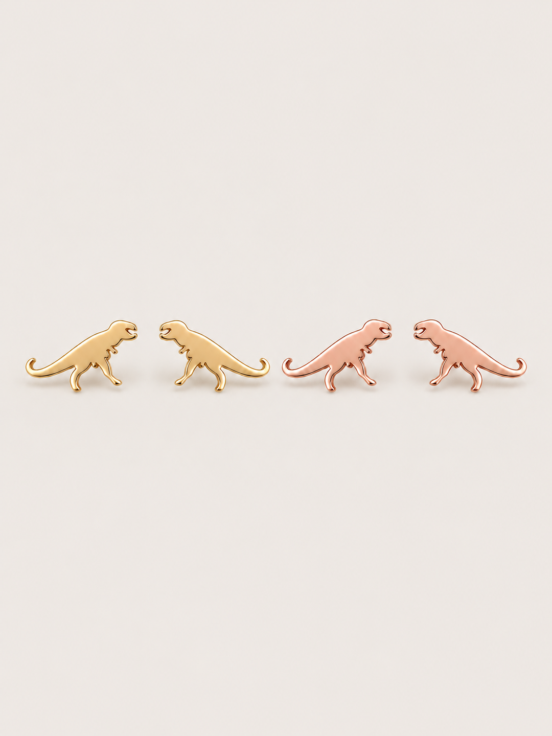 Gold and Rose Gold T-Rex Dinosaur Stud Earrings shown on a warm neutral background