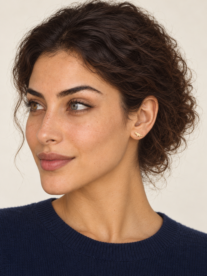 Gold T-Rex Dinosaur Stud Earring worn on the viewer-right ear
