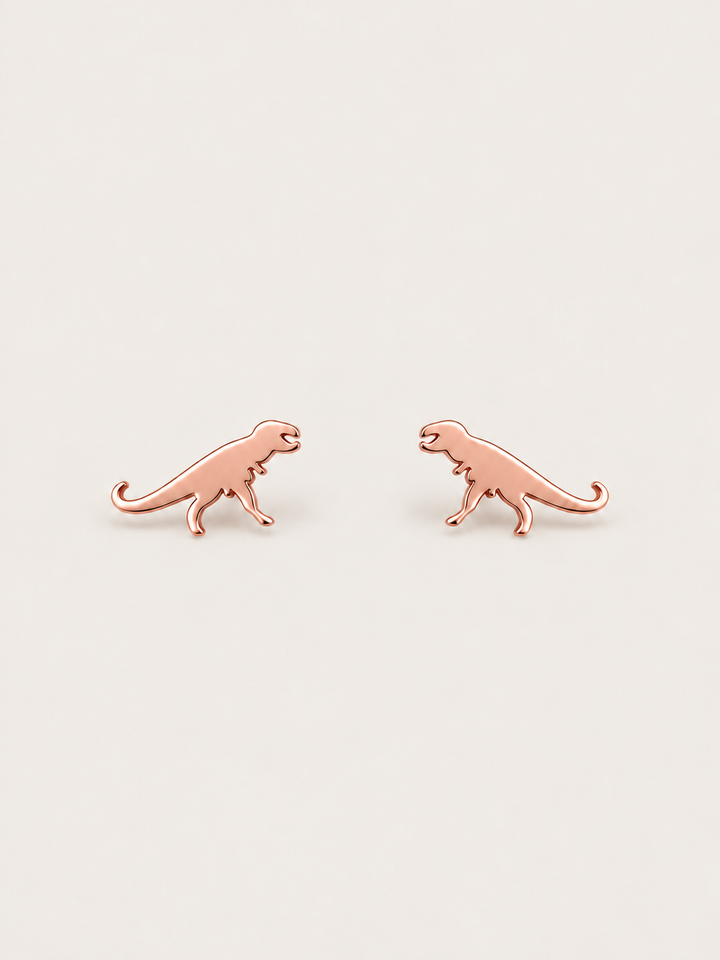 Rose Gold T-Rex Dinosaur Stud Earrings shown on a warm neutral background