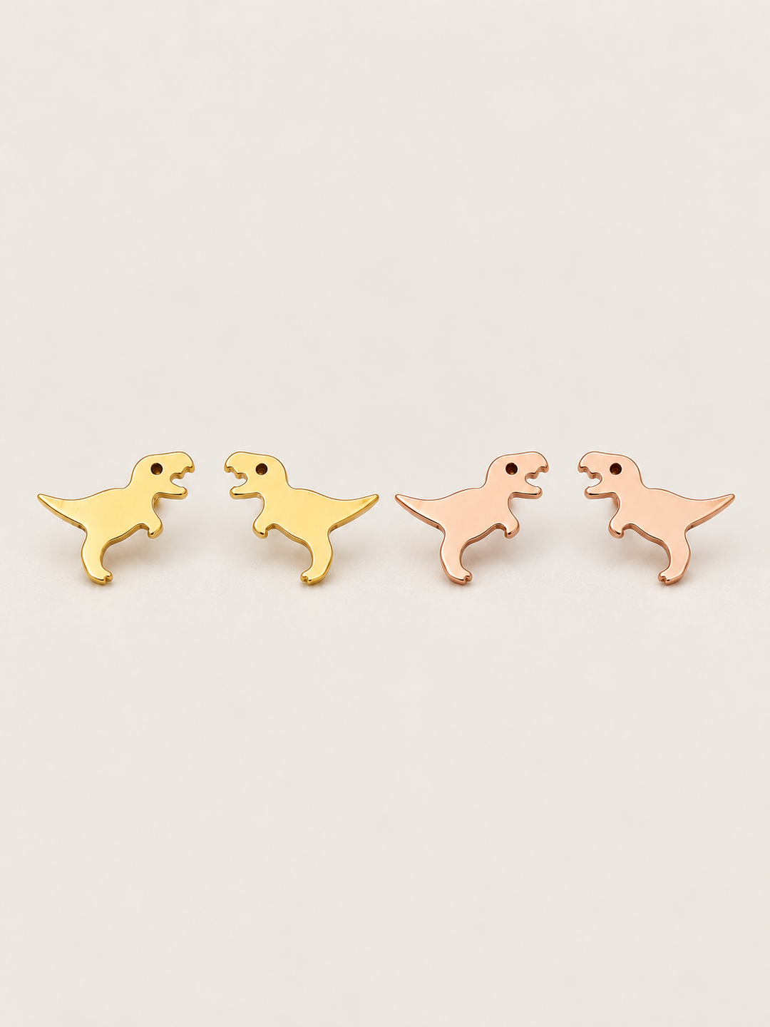 T. Rex Stud Earrings in gold and rose gold shown on a warm neutral background