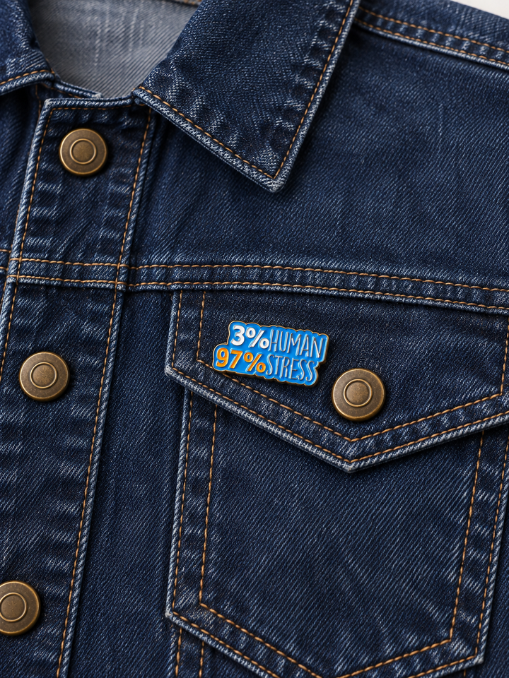 3 Percent Human 97 Percent Stress Pin displayed on a dark indigo denim jacket beside a metal button