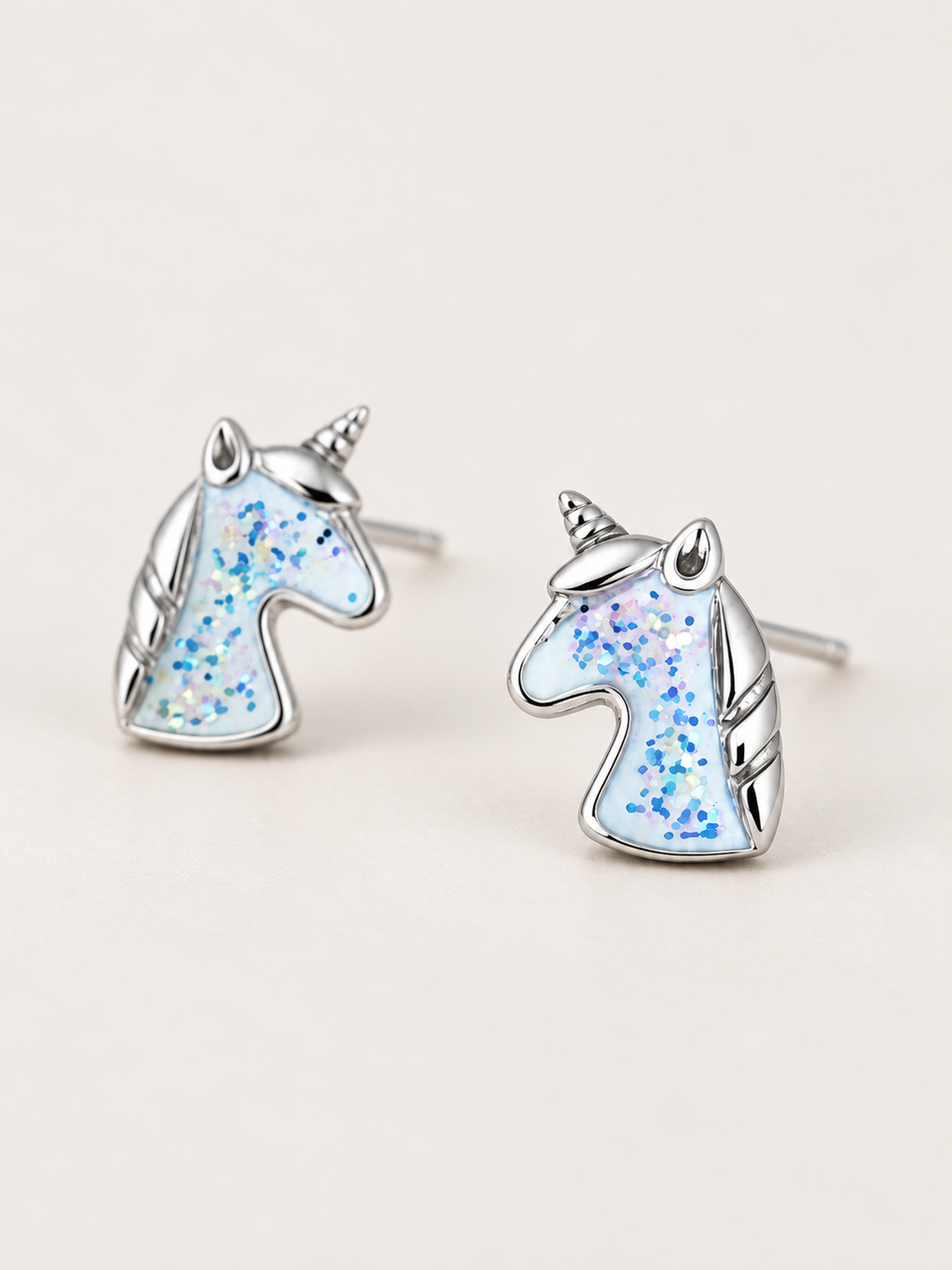 Unicorn Stud Earrings shown angled on a warm neutral background