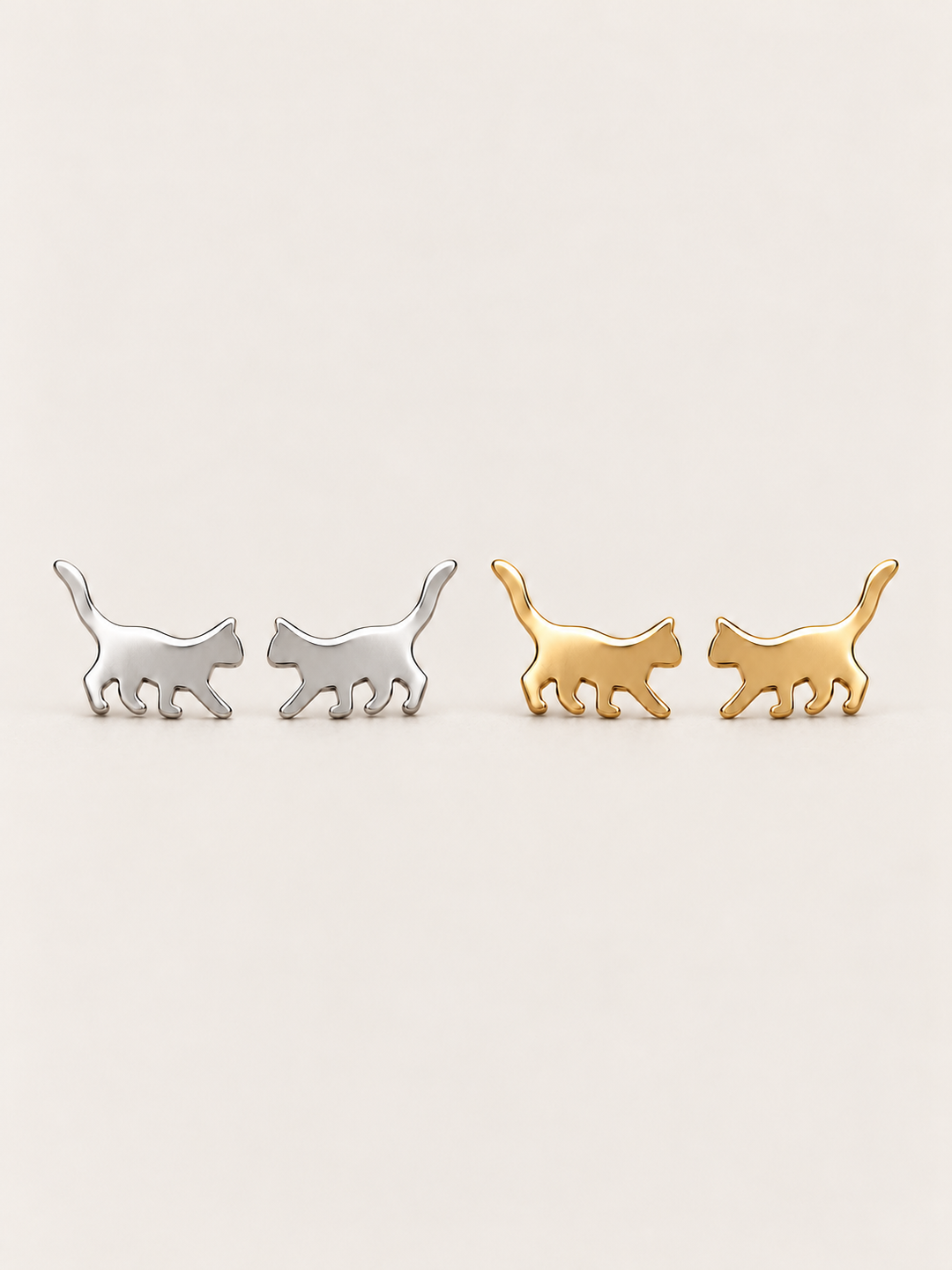 Walking Cat Stud Earrings in Silver and Gold shown on a warm neutral background