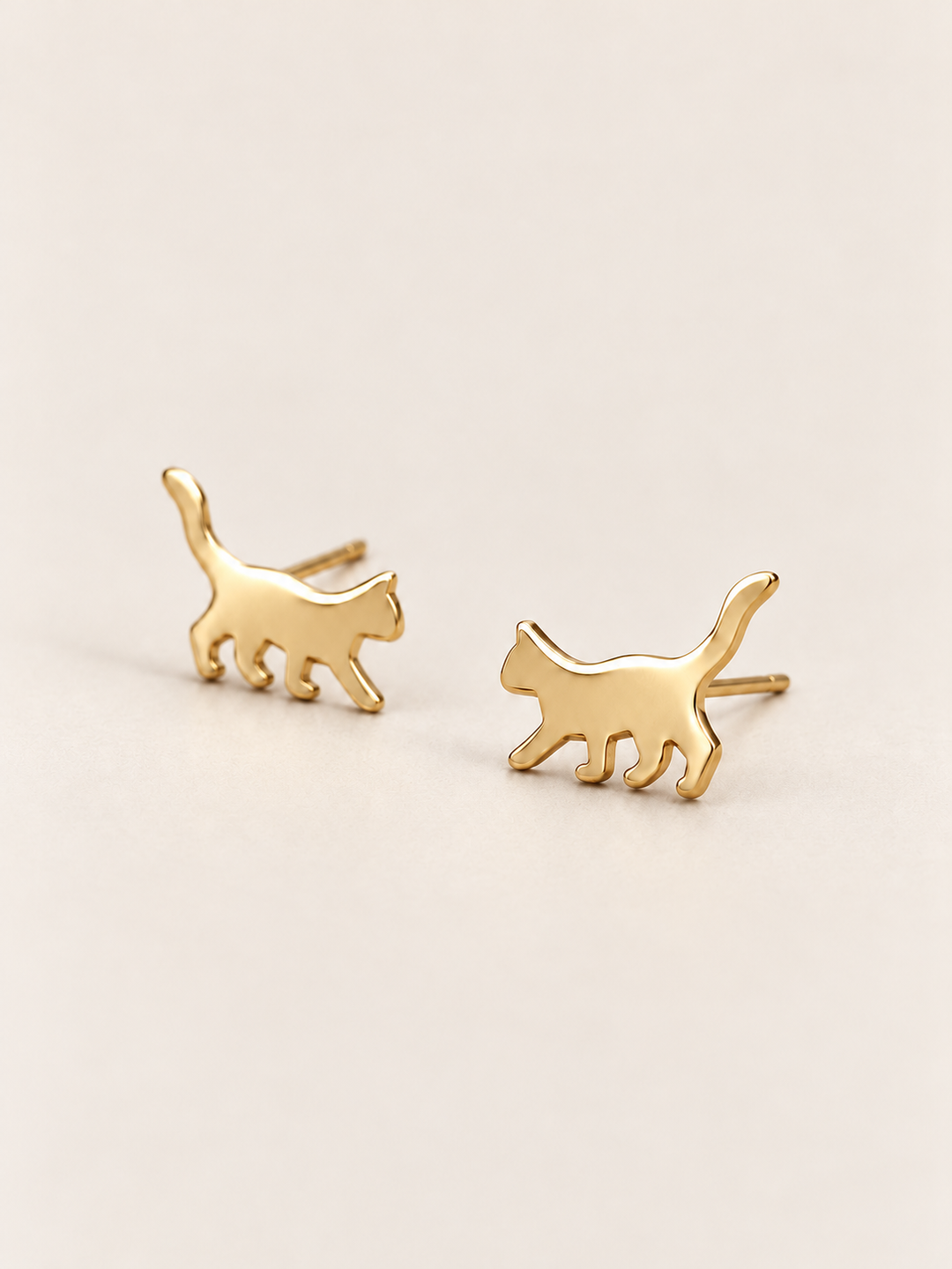 Gold Walking Cat Stud Earrings shown angled on a warm neutral background
