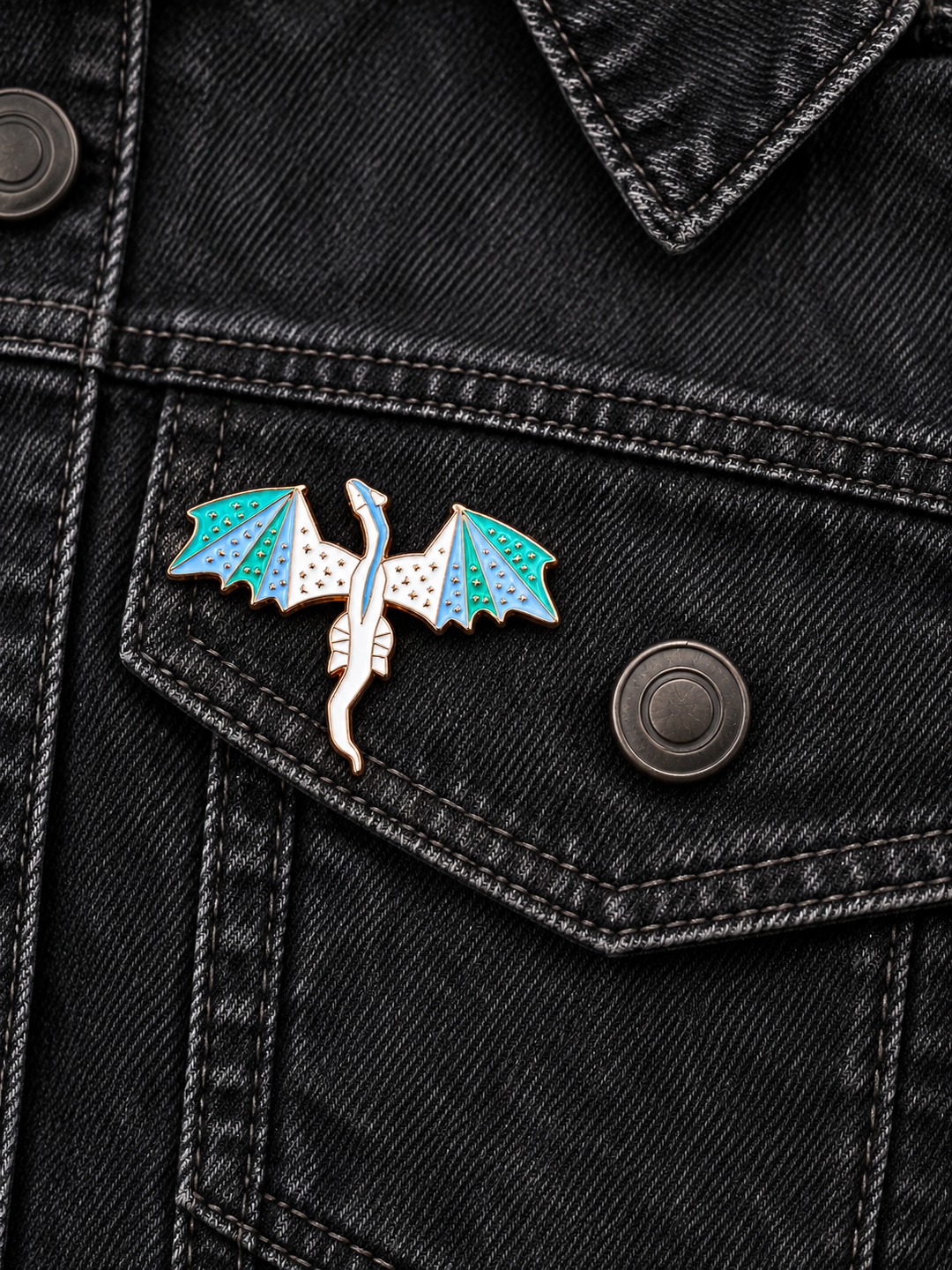 White Dragon Pin displayed on a black denim jacket beside a metal button