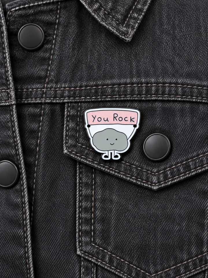 You Rock Cute Rock Pin displayed on a charcoal denim jacket beside a metal button