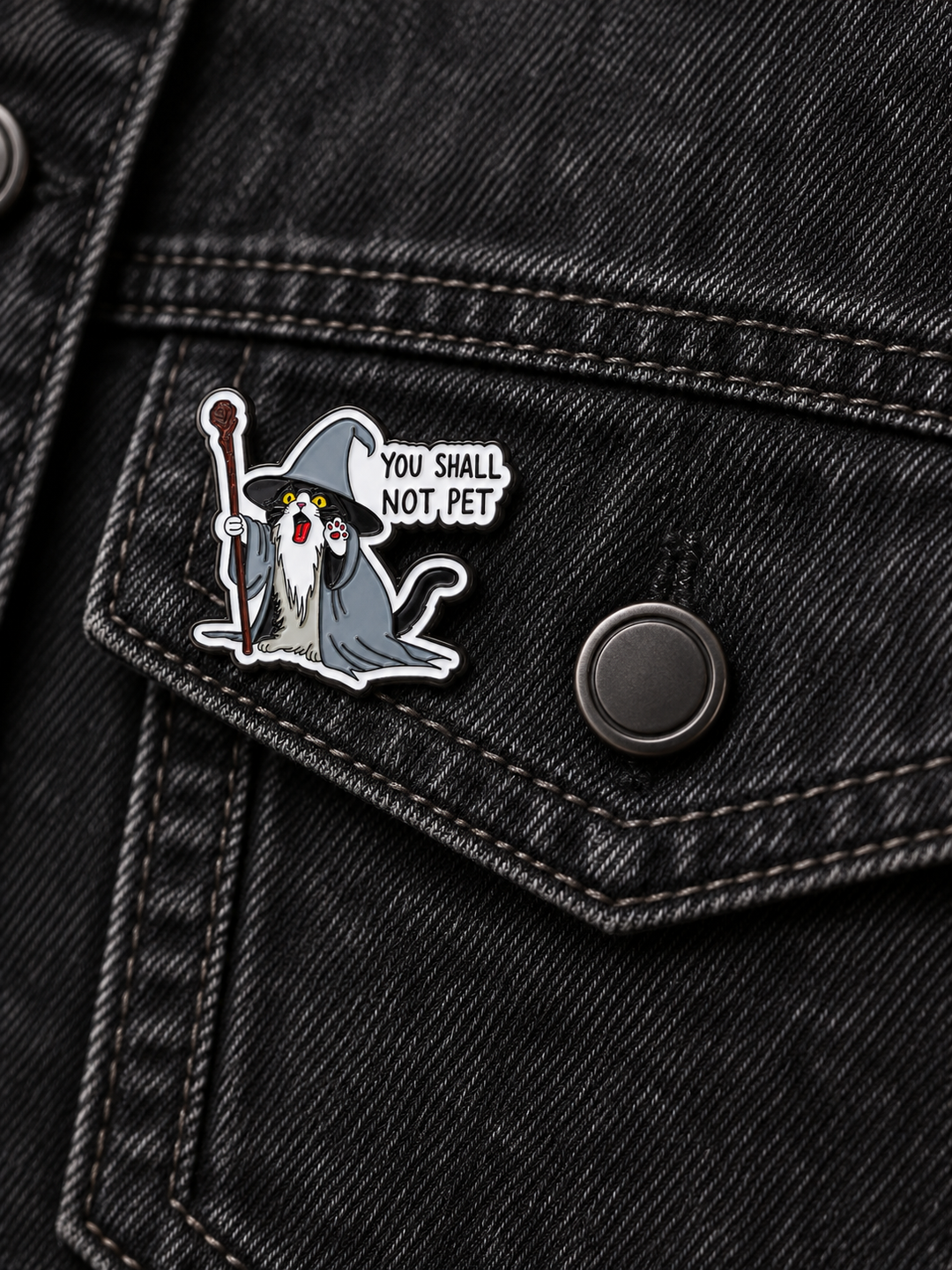 You Shall Not Pet Wizard Cat Pin displayed left of a centered button on a black denim pocket
