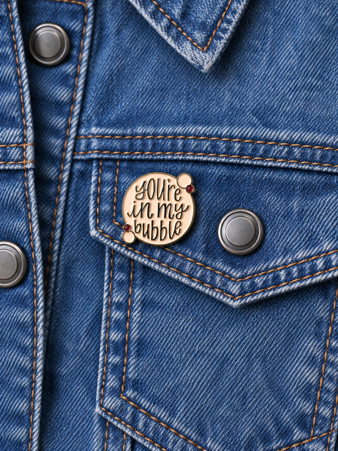 You’re in My Bubble Pin displayed on a stonewash denim jacket beside a metal button